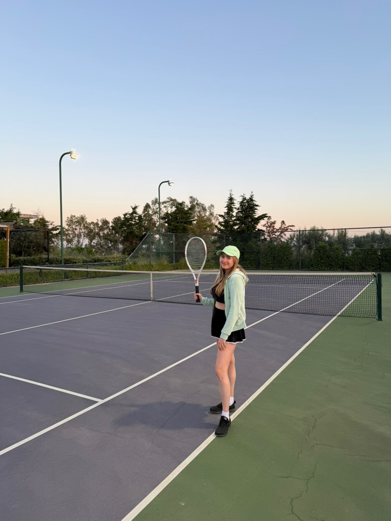 Patrycja today, holding a tennis racket on a court at dusk